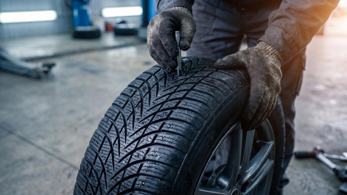 Měření hloubky dezénu zimní pneumatiky měrkou, kontrola před zimou
